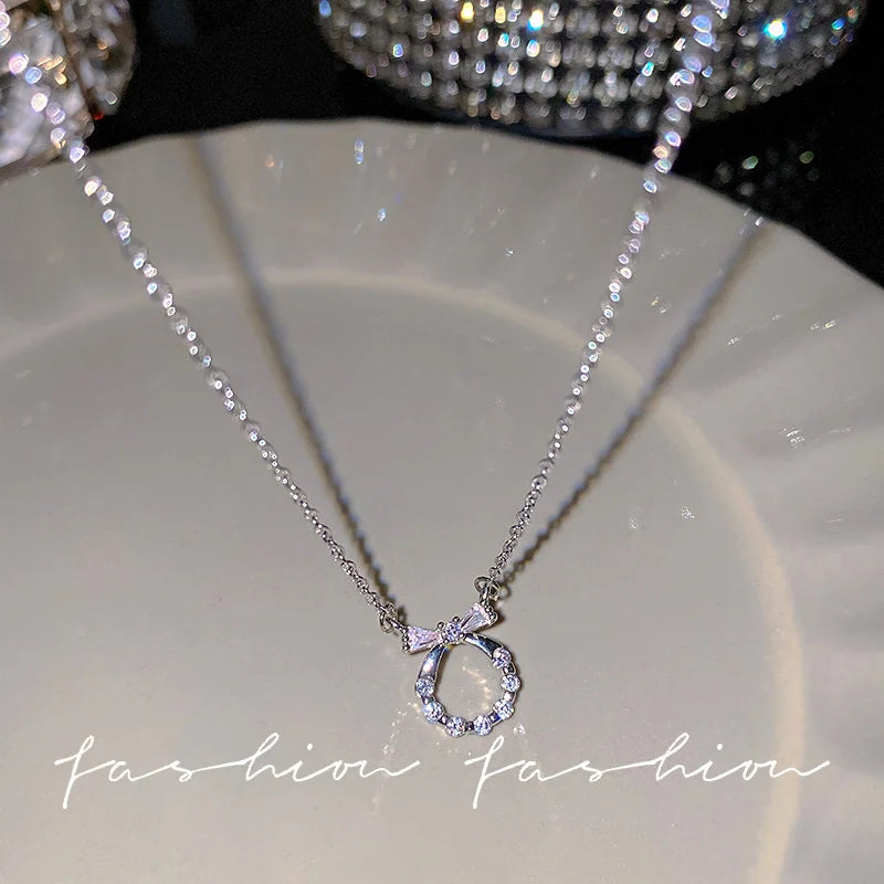 Silver crystal bow angel wings heart pendant necklace displayed on a light surface.