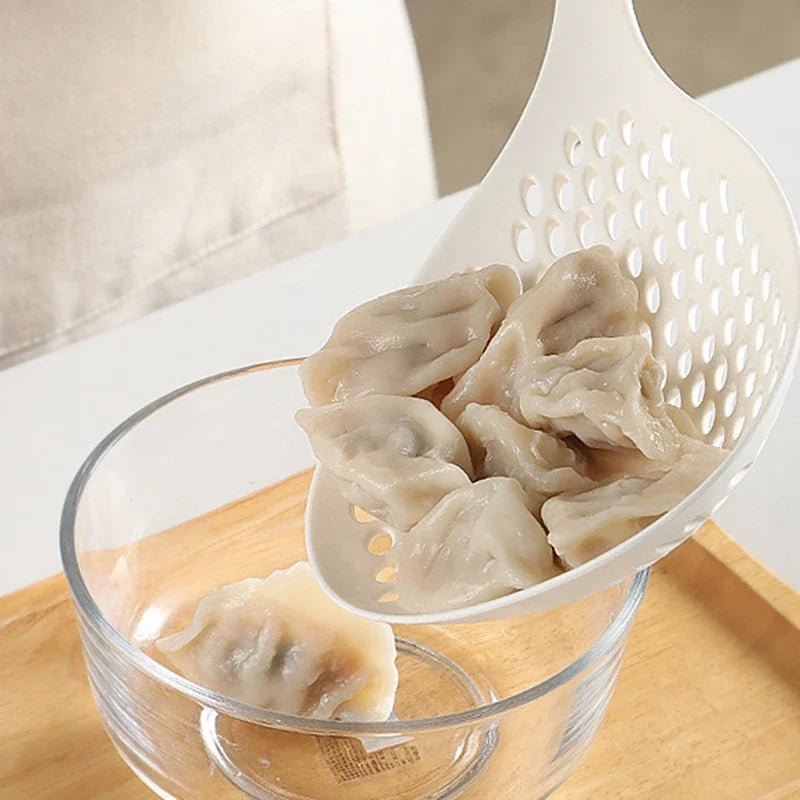 A white strainer spoon holds several translucent dumplings in a glass bowl on a wooden board.