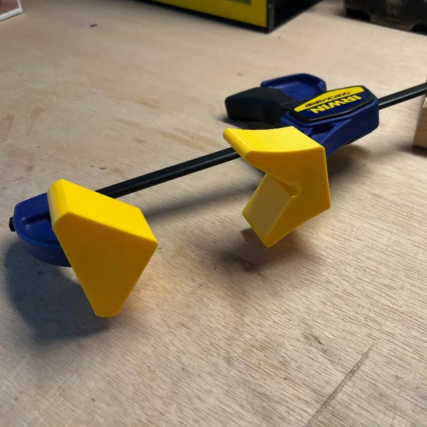 A yellow and blue quick clamp angle adapter tool used for woodworking.