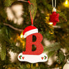 Rød glitter-akryl bokstav B på hvit base, hengende på et juletre.
