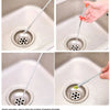 A hand uses a flexible drain snake to clear a clogged sink drain.