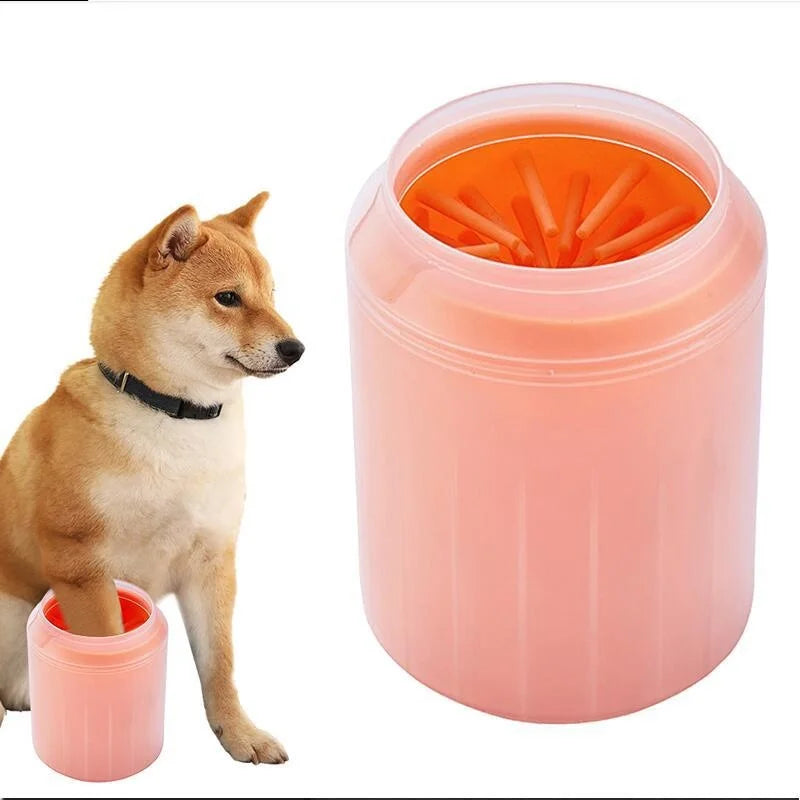 A light brown dog stands next to a pink plastic cup containing orange silicone combs for cleaning paws.