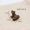 Liten vintage messingfrosk miniatyrfigur på beige stoff med dimensjonslinjer.
