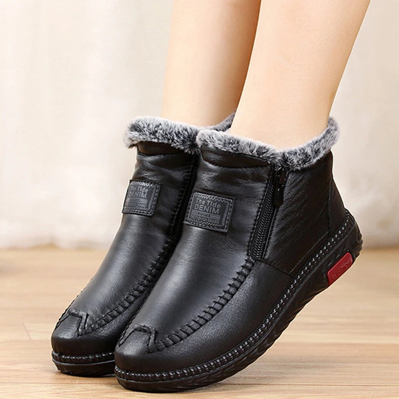 Ein Paar schwarze wasserdichte Chelsea-Winterstiefel mit grauem Kunstfellfutter auf einer Holzoberfläche