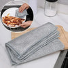 A stack of gray scratch-free microfiber cleaning cloths is shown next to a plate with food residue.