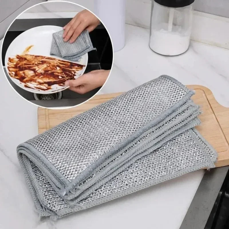 A stack of gray scratch-free microfiber cleaning cloths is shown next to a plate with food residue.