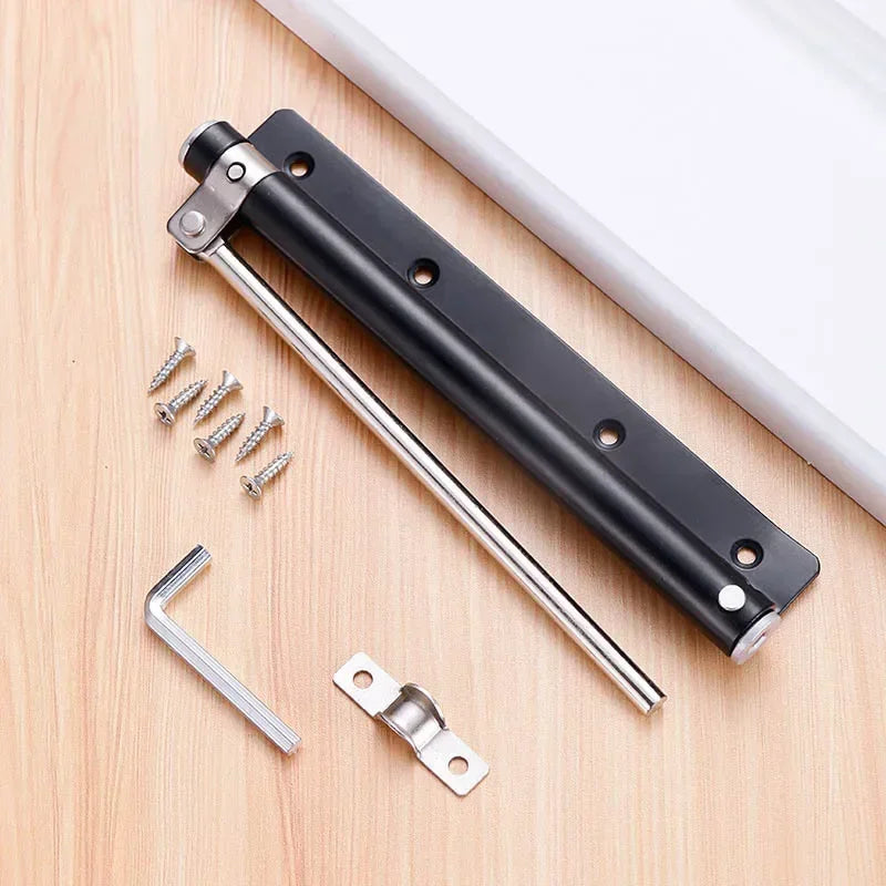 A black stainless steel automatic door closer with an invisible spring mechanism and mounting hardware on a wooden surface.