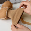 A pair of tan suede leather winter booties with a soft fur lining being held by a person.