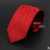 Corbata de seda roja con estampado ornamentado, enrollada sobre fondo oscuro.