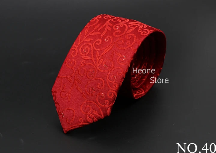 Corbata de seda roja con estampado ornamentado, enrollada sobre fondo oscuro.