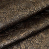 Close-up of dark brown vintage floral textured faux leather fabric rolled and draped.