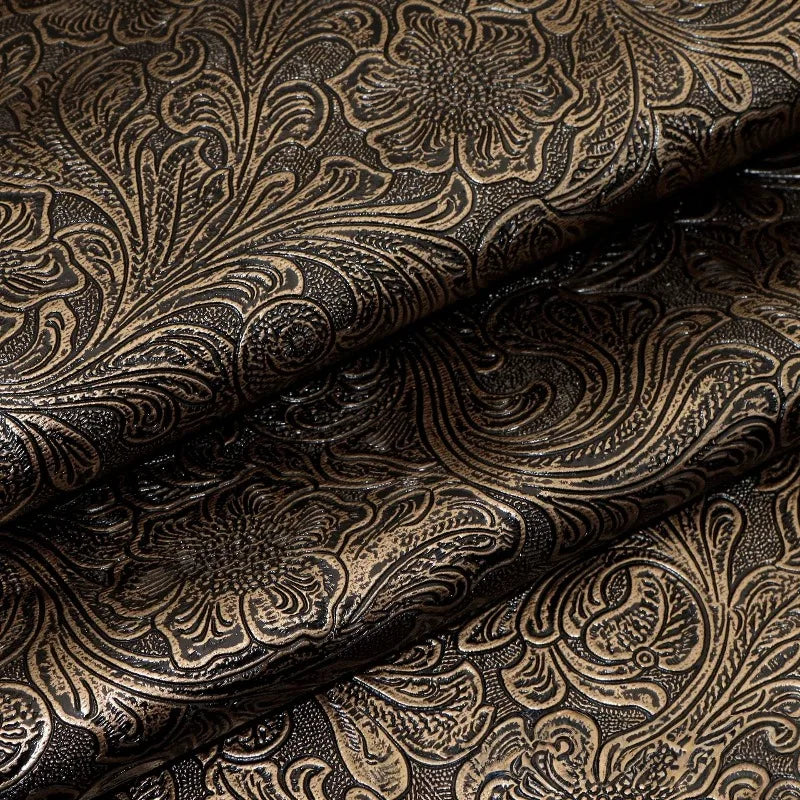 Close-up of dark brown vintage floral textured faux leather fabric rolled and draped.