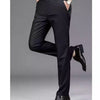 A man models black stretch straight-leg trousers with a white shirt and a wristwatch.