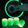 Several bright green glow-in-the-dark tire valve caps are shown next to a dark background with a glowing green ring.