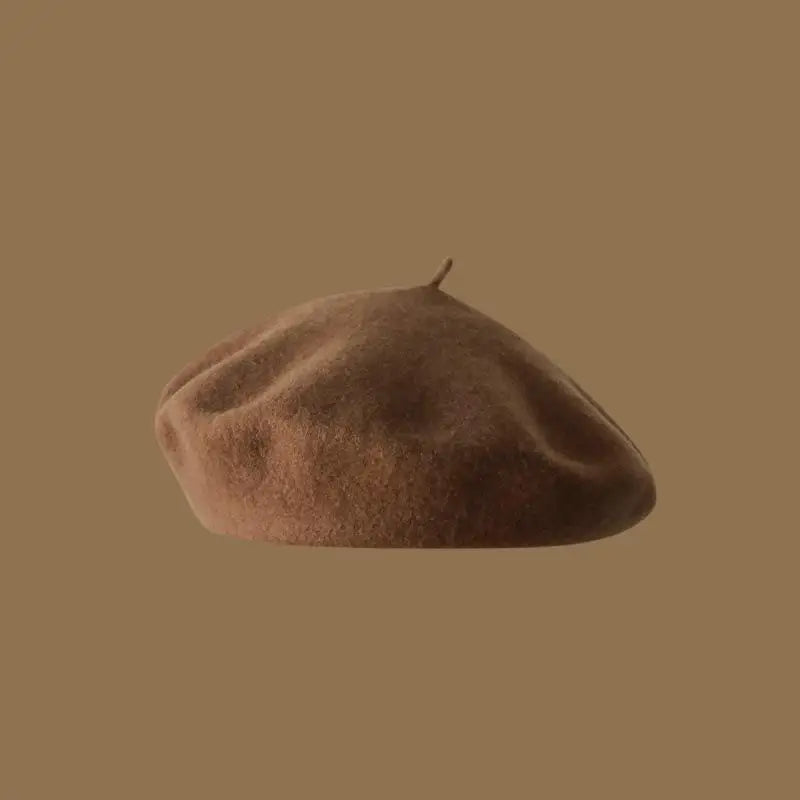 A close-up view of a brown wool beret hat resting on a plain background.