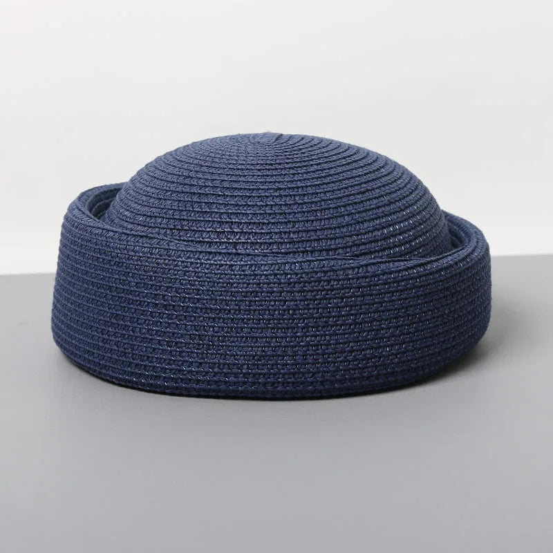 A navy blue straw pillbox sun hat with a wide brim shown from above.