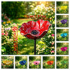 A vibrant red handcrafted metal flower garden stake shaped like a bowl, set in a lush green garden.