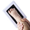 A handprint and footprint keepsake kit showing a baby's foot placed inside a white frame.