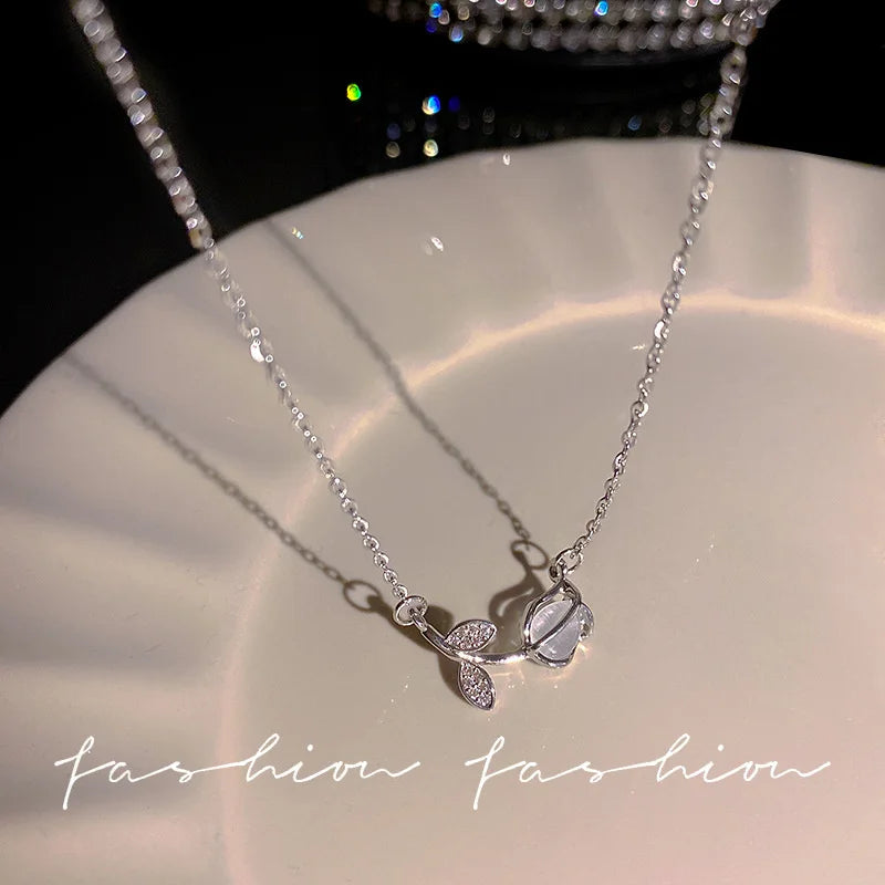 Silver heart pendant necklace featuring crystal bow angel wings design displayed on a white plate.