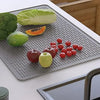 A silicone stove protector mat features various fresh vegetables and fruits placed on it.