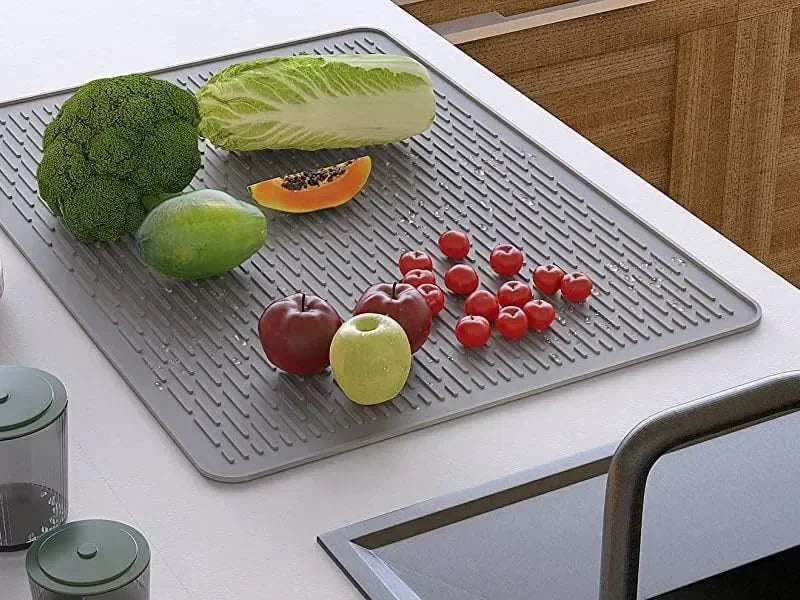 A silicone stove protector mat features various fresh vegetables and fruits placed on it.