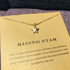 Collar colgante de estrella delicada en oro sobre tarjeta amarilla con texto que anima a la alegría y el éxito.