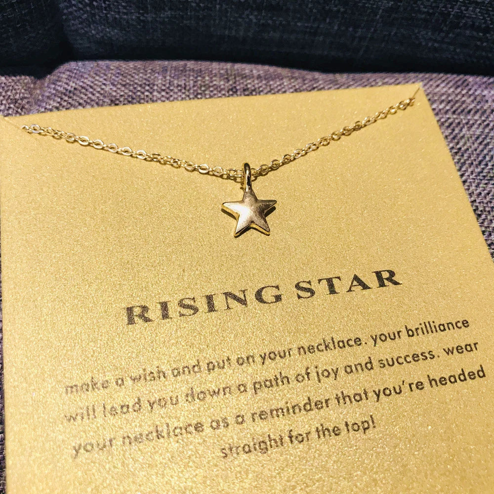 Collar colgante de estrella delicada en oro sobre tarjeta amarilla con texto que anima a la alegría y el éxito.