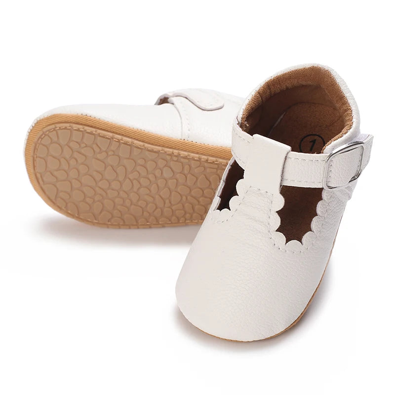 A pair of white soft non-slip baby first walker shoes with light tan soles and suede lining.