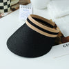A black woven straw sun hat with a beige and black striped brim resting on a white surface.