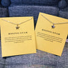 Collar colgante delicado de estrella en tono dorado sobre tarjeta amarilla con texto inspirador.