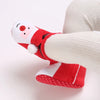 A close-up of a red baby winter ankle boot with a white plush lining and a festive face design.