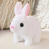 A white plush rabbit toy with pink inner ears sitting on a light surface.