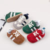 A collection of five baby first walker shoes in various colors and styles, including green, beige, gray, brown, and red.