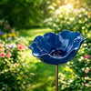 A handcrafted metal blue flower garden stake shaped like a bowl or bird bath in a sunny garden setting.