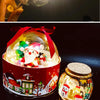 A festive red tin container filled with LED fairy lights shaped like a Santa Claus and reindeer, next to a glass jar of gold-