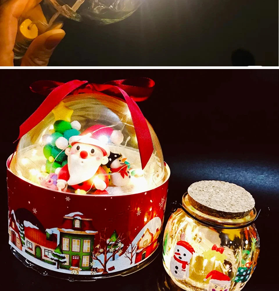 A festive red tin container filled with LED fairy lights shaped like a Santa Claus and reindeer, next to a glass jar of gold-