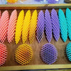 Bandeja de madera con varios juguetes antiestrés de gusano 3D coloridos y elásticos en formación de cuadrícula.