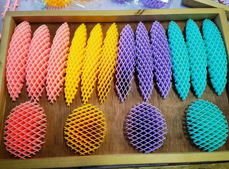 Bandeja de madera con varios juguetes antiestrés de gusano 3D coloridos y elásticos en formación de cuadrícula.