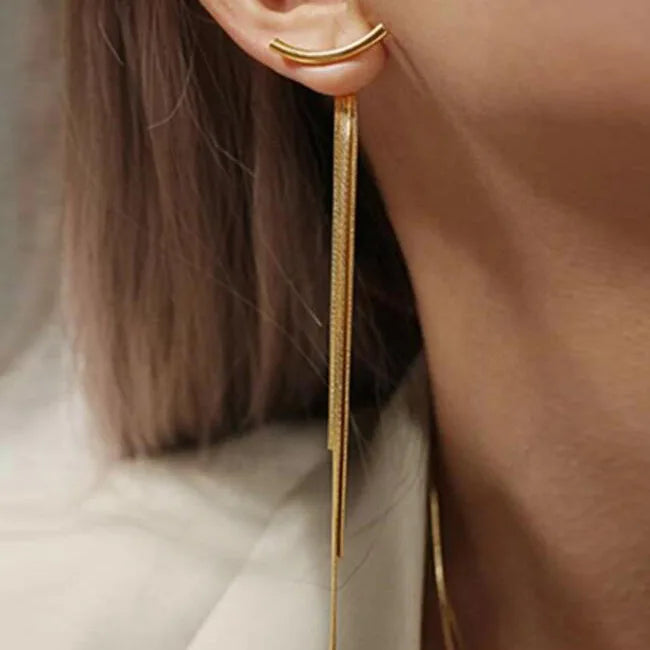 Gold geometric tassel drop earrings hanging from an ear