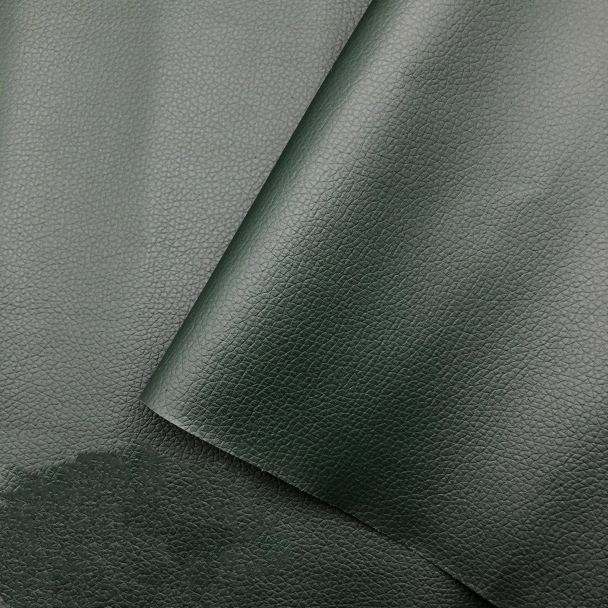 Primer plano de un parche autoadhesivo de cuero verde oscuro aplicado sobre un mueble.