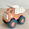 A toy bulldozer vehicle in orange and white, featuring a cab, large tires, and a shovel-like bed.