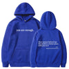 Ein königsblauer Hoodie mit der Aufschrift „Du bist genug“ und dem Satz „Liebe Person hinter mir, die Welt ist ein besserer O