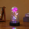 Fortryllet galakse-rose med LED-félys inne i en glasskuppel på en treoverflate.