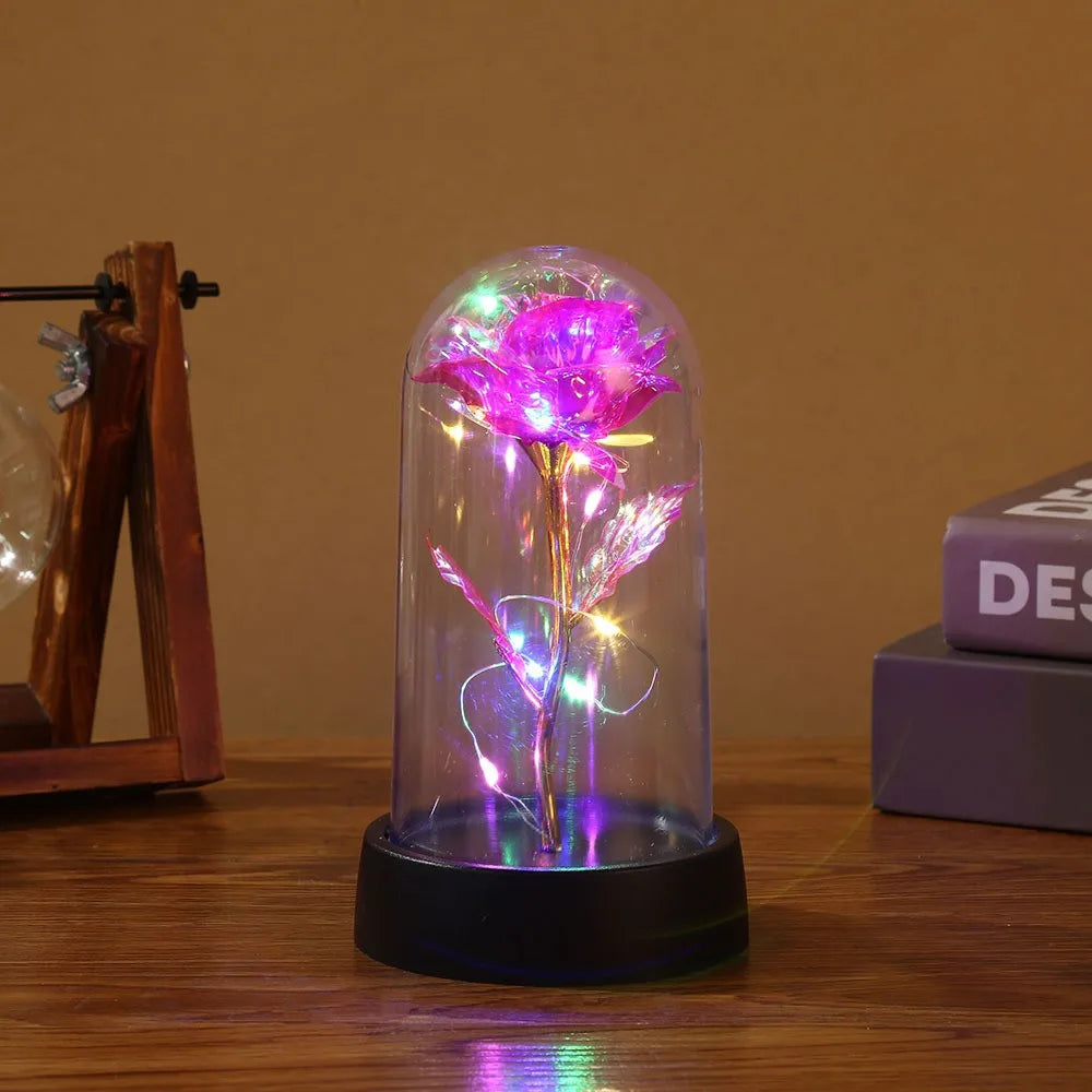 Fortryllet galakse-rose med LED-félys inne i en glasskuppel på en treoverflate.
