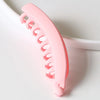 Broche de banana acrílico color rosa con acabado escarchado, visto en primer plano en el cabello.
