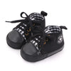 A pair of black canvas baby sneakers with a checkered pattern and a soft non-slip sole.
