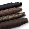 Rolls of vintage floral textured faux leather fabric in various shades of brown and black for handcrafted projects