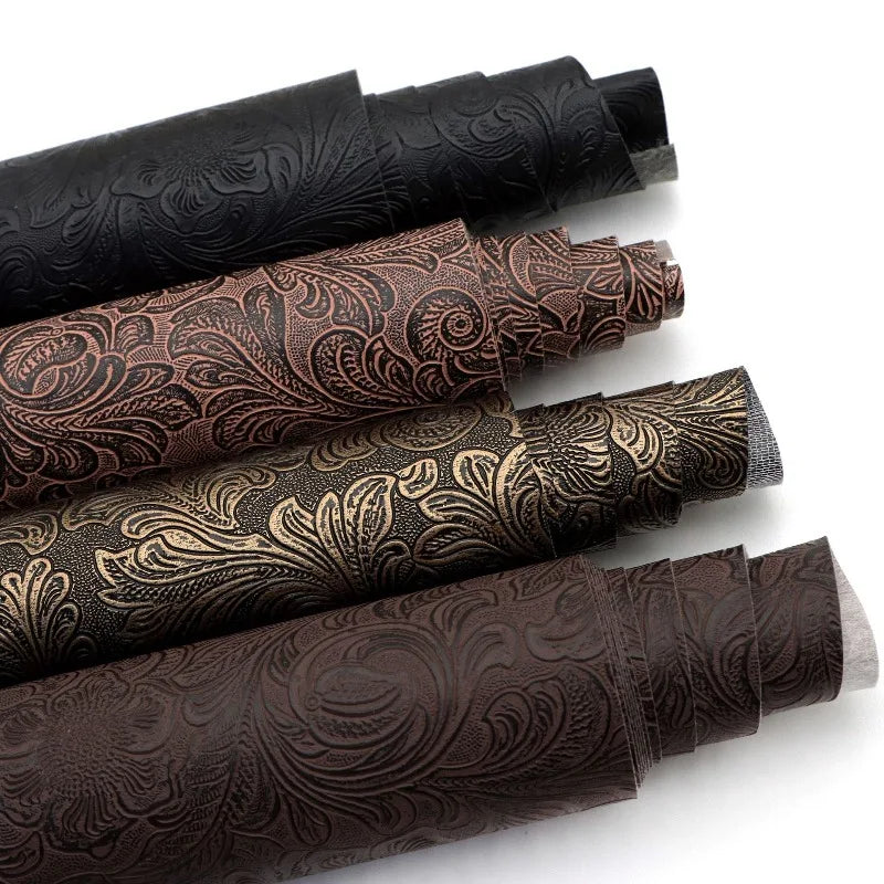 Rolls of vintage floral textured faux leather fabric in various shades of brown and black for handcrafted projects