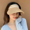 A woman wearing a beige woven straw sun hat with a wide brim and a light blue knitted top.