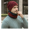 A man wearing a maroon knit beanie and matching scarf over a gray sweater.